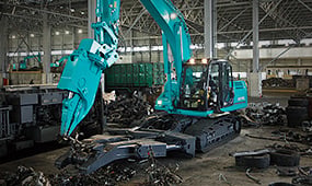 コベルコの専用破砕・選別アタッチメント付き重解体用油圧ショベルがスクラップヤードで作業中。