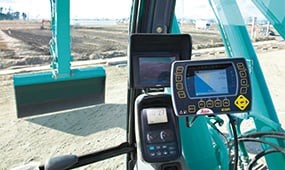 運転席のモニターと操作パネル。3Dマシンガイダンスや情報表示技術。